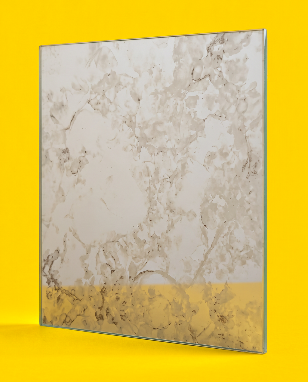 Antique mirror glass panel in the Silver Night pattern, pale silver grey with soft clouds and fine dark veins, on a yellow background