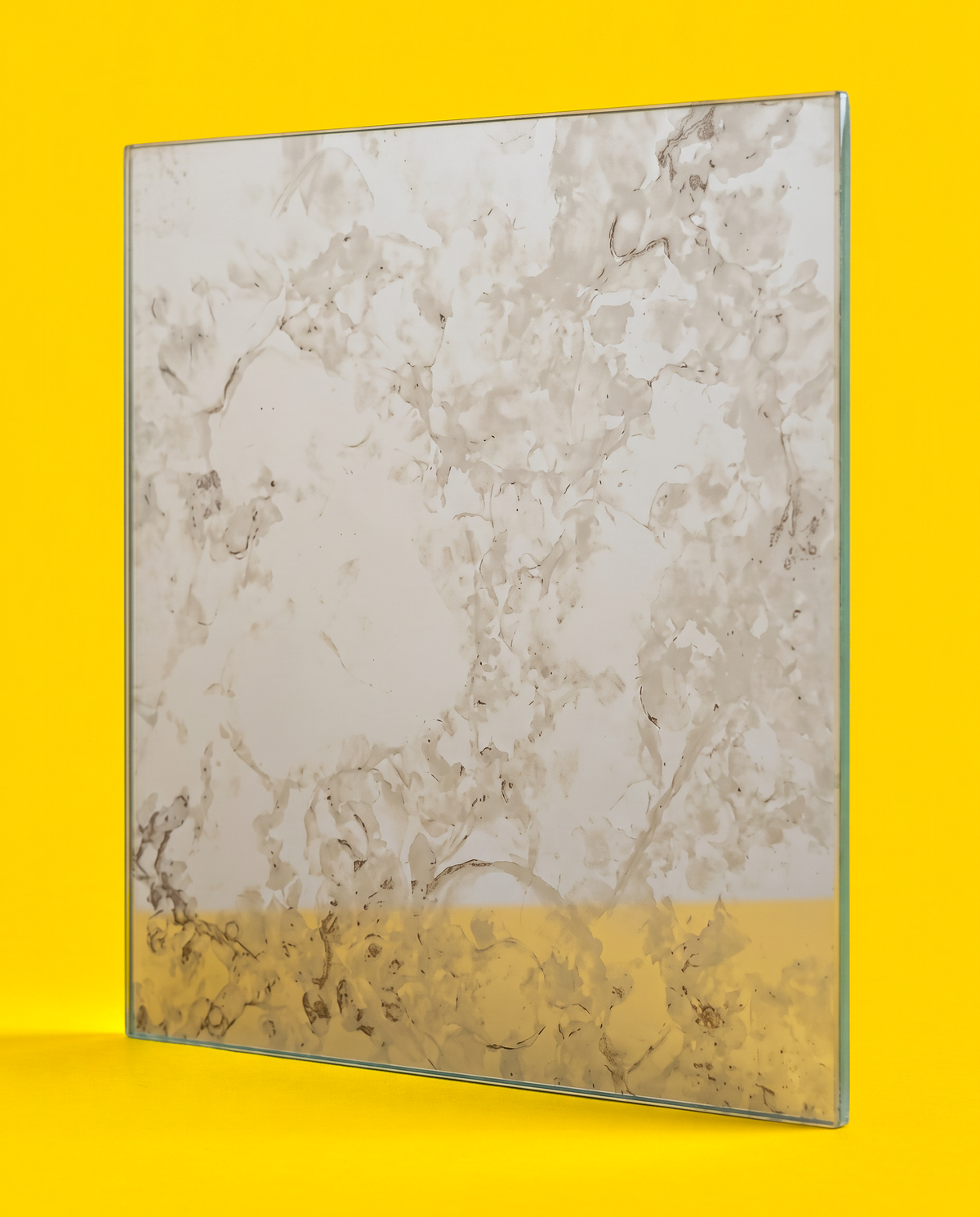 Antique mirror glass panel in the Silver Night pattern, pale silver grey with soft clouds and fine dark veins, on a yellow background
