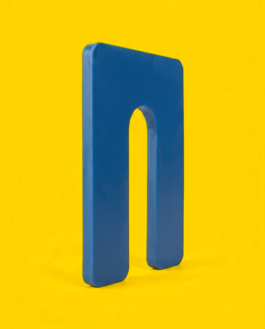 Blue 1/16 inch horseshoe shim, 3 by 4 inch plastic, standing on edge showing the moulded edge and the U-slot