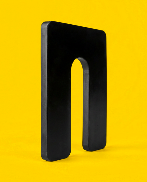 Black 1/4 inch plastic horseshoe shim, 3 by 4 inch, standing upright showing the U-slot and the moulded edge thickness