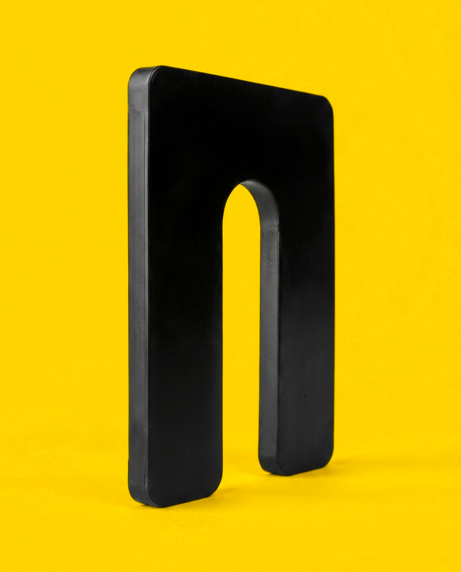 Black 1/4 inch plastic horseshoe shim, 3 by 4 inch, standing upright showing the U-slot and the moulded edge thickness
